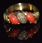 An 18ct gold ring set with three round cut diamonds and two coral cabochons, 5.2g, size L