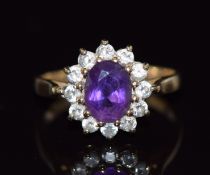 A 9ct gold ring set with an oval cut amethyst surrounded by cubic zirconia, 2.6g, size O