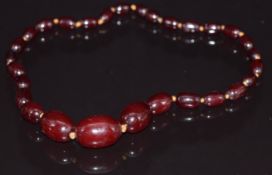 A cherry amber necklace made up of 27 oval beads, largest bead 2.5 x 1.7cm, 29.6g