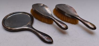 George V hallmarked silver three piece dressing table set comprising hand mirror and two brushes,