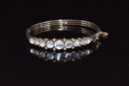 A c1900 silver bangle set with moonstones and seed pearls
