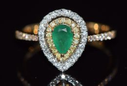 An 18ct gold ring set with a pear cut emerald surrounded by yellow diamonds and diamonds, 3.1g, size