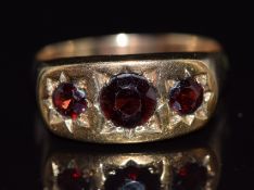 A 9ct gold ring set with three round cut garnets in star settings, 4.2g, size U