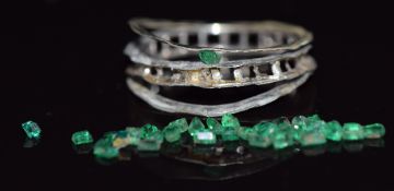A white gold ring mount together with loose emeralds