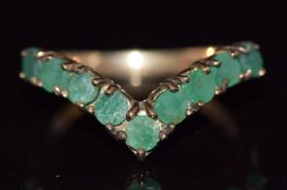 A 9ct gold ring set with round cut emeralds in a V shape, 2.7g, size M