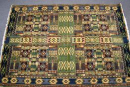 A large rug with geometric designs on a green ground with attached John Lewis label 'Marco Polo',