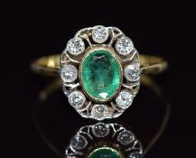 An 18ct gold ring set with an oval cut emerald surrounded by diamonds in a pierced setting, 3.3g,