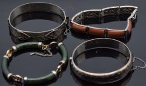 A silver bangle set with garnets, another silver bangle with engraved floral decoration, a silver