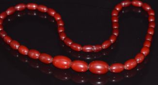 A  cherry amber necklace made up of 43 graduated oval beads, 33.6g, largest bead 2 x 1.3cm