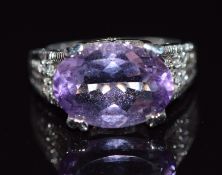 A 9k white gold ring set with an oval cut amethyst and diamonds to the shoulders and mount, 5.9g,