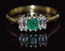 An 18ct gold ring set with an emerald cut emerald and two emerald cut diamonds, approximate