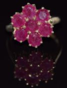 A 9ct gold ring set with round cut rubies in a cluster, 4.7g, size O