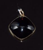 A yellow metal pendant set with a garnet cabochon