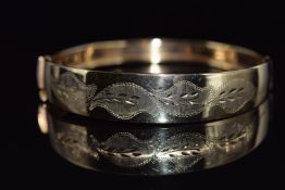 A 9ct gold bangle with cut out foliate decoration, 10.5g