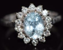 An 18ct white gold ring set with an oval cut aquamarine surrounded by diamonds, 4.6g, size K