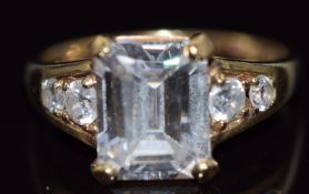 A 9ct gold ring set with an emerald cut cubic zirconia and further round cut cubic zirconia to the