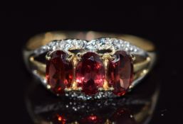 A 9ct gold ring set with oval cut garnets, 1.4g, size N
