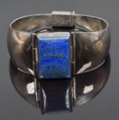 A silver bangle set with a rectangular lapis lazuli cabochon, 54.8g (5.4 x 6.2cm)