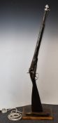 Enfield pattern percussion hammer action gun converted to a standard lamp, mounted on a wooden
