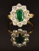 An 18ct gold ring set with an oval cut emerald of approximately 1.5ct and ten round cut diamonds,