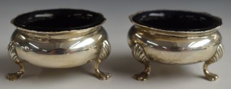 Pair of George V hallmarked silver salts, raised on three feet and with blue glass liners,