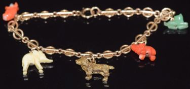 A 9ct gold charm bracelet set with a coral elephant, coral pig, jade dog, yellow metal dog and an