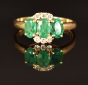 An 18ct gold ring set with three oval cut emeralds and diamonds, size O/P, 3.8g