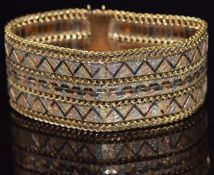 A 15ct gold tri-coloured bracelet with matt decoration and zigzag lines with curb link borders,