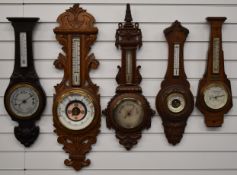Five circa Edwardian aneroid wall barometers in carved wooden cases, to include one with silvered