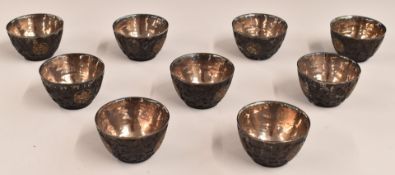 Set of nine late 19th/ early 20thC Chinese carved coconut shell or similar silver lined wine cups