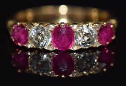 A c1900 18ct gold ring set with cushion cut rubies and old cut diamonds in a scrolling setting,