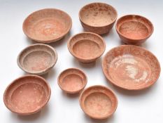 Nine Roman redware pottery bowls/dishes including two near pairs, some with incised or relief