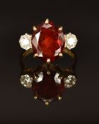 An 18ct gold ring set with an oval cut garnet and two round cut diamonds, size K/L, 5.4g