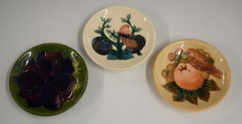 Three Moorcroft pin dishes, one decorated with birds and fruit the other in Clematis pattern