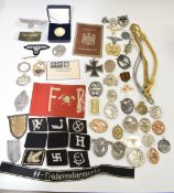 Approximately fifty replica German Nazi insignia and badges including metal and cloth examples