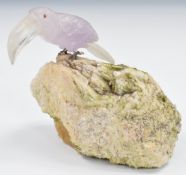 A quartz toucan with clear bill and pink body, with cabochon red stone eyes and silver claws