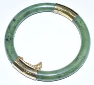 Chinese nephrite jade bangle with yellow metal mounts and safety chain, 7.7cm diameter