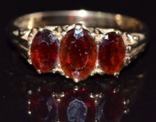 A 9ct gold ring set with three oval garnets, size O, 2.7g