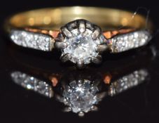 An 18ct gold ring set with a diamond measuring approximately 0.25cts with further diamonds to the