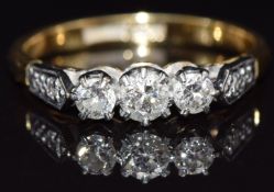 An 18ct gold ring set with three diamonds in a platinum setting,  with two further diamonds to the