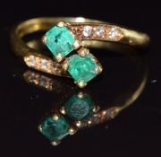 An 18ct gold ring set with two emeralds and diamonds, size M, 3.4g