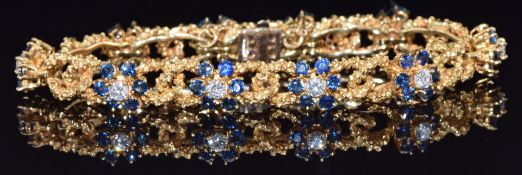 An 18ct gold textured bracelet set with ten 0.2ct diamonds each surrounded by six sapphires in