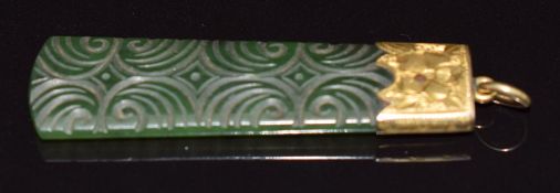 A carved nephrite jade pendant mounted in a 9ct gold pendant with engraved decoration