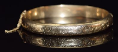 A 9ct gold bangle with engraved scrolling decoration, 10.8g
