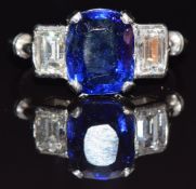 A platinum ring set with a cushion cut sapphire of approximately 3.1cts, flanked by a diamond of