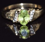 A 9ct gold ring set with an oval cut peridot and diamonds, size M, 2.5g