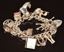 A silver charm bracelet with 11 silver charms including 10 shilling note, church, keys, rings,