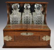 Late 19th or early 20thC oak three bottle tantalus, with twin flaps opening to reveal six drinking