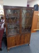 An Edwardian mahogany double door glazed bookcase fitted with cupboards below