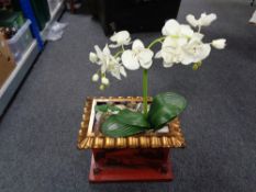 An oriental style planter containing artificial plants with pebbles.